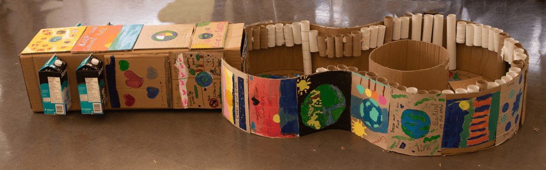 the middle of a cardboard guitar with messages for the planet