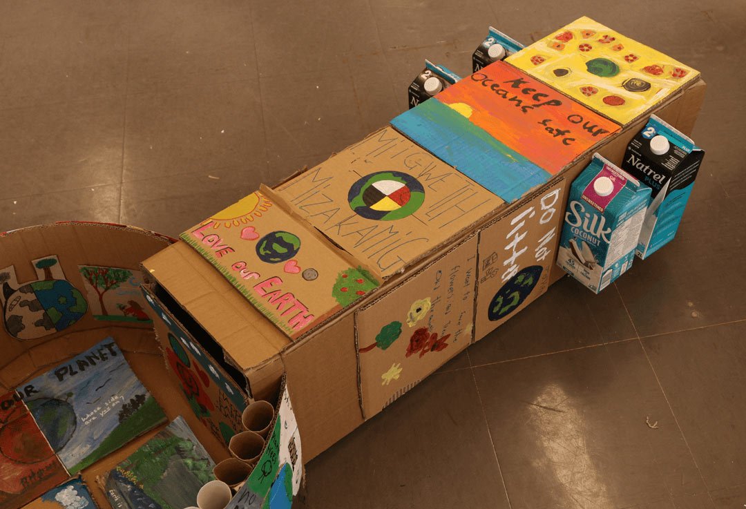 the top of a cardboard guitar with messages for the environment