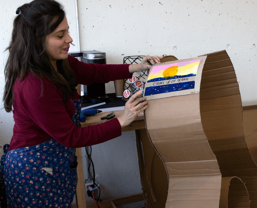 Orfelina is pasting a decoration that reads clean up our oceans to a cardboard guitar