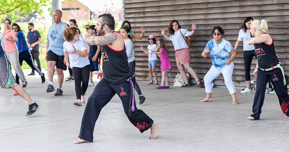 Instructor teaching a group of participants the ginga, a rocking move in triangle formation.