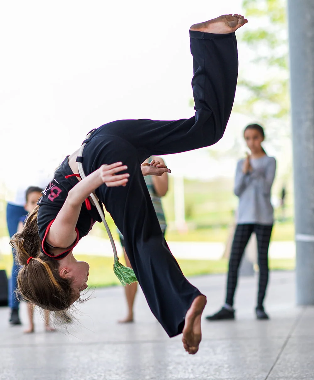 A young participants mid-jump with both hands and feet off the ground.