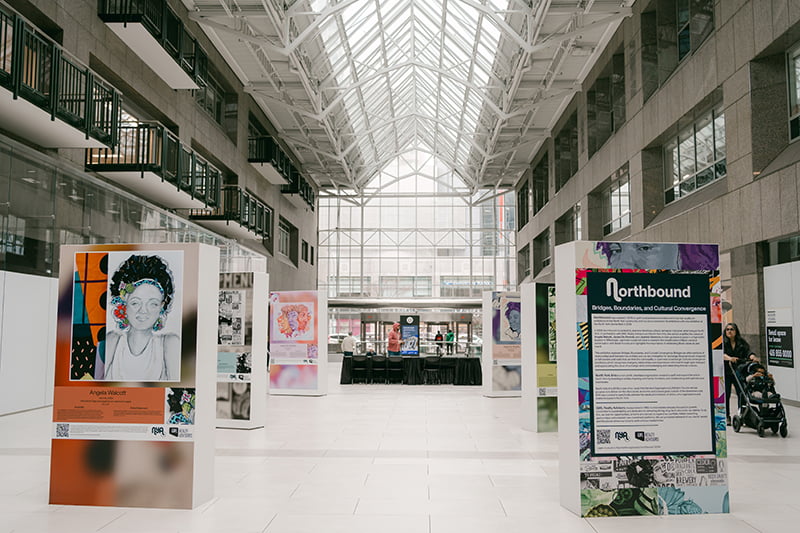 Six artworks on big boxes in the atrium of the North Centre lobby. Photo by Maria Vega